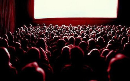 Crowd watching movie in theatre, rear view